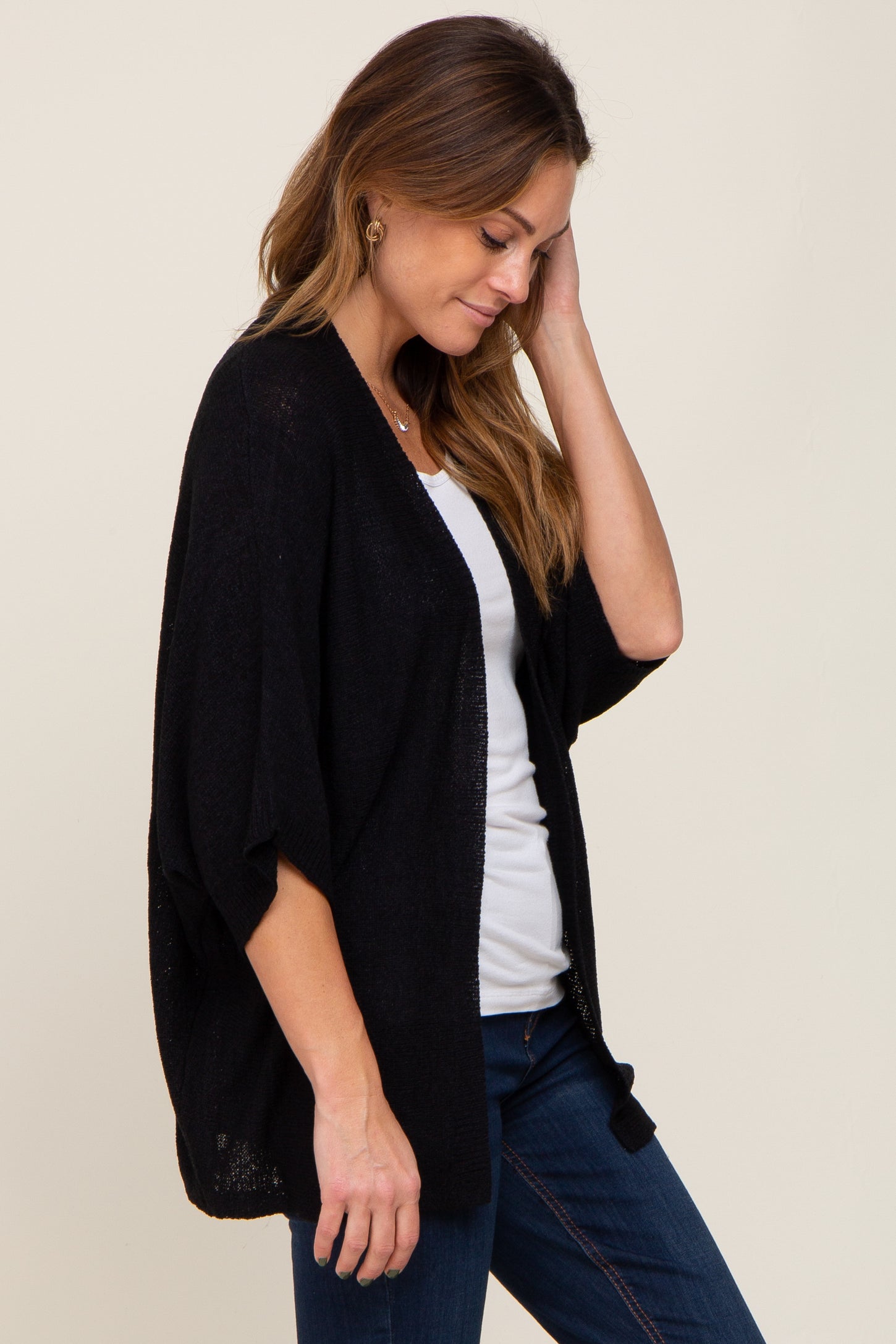 woman wearing a black open-front kimono cardigan over a white top with jeans