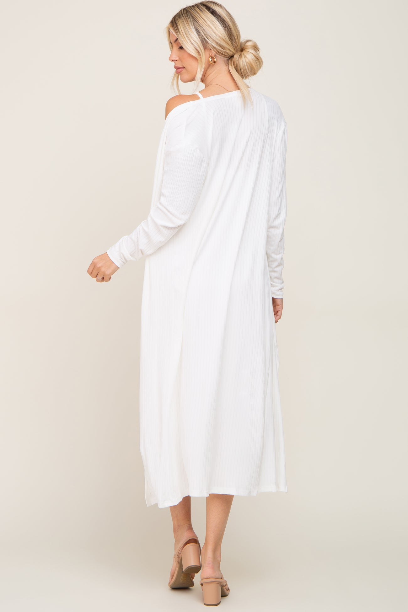woman wearing a white long sleeve dress with a relaxed fit and open shoulder detail, viewed from the back