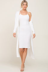 woman wearing a white ribbed midi dress with a long white cardigan and heeled sandals