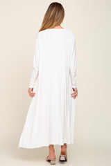 woman wearing a long white ribbed maternity dress with long sleeves, seen from the back