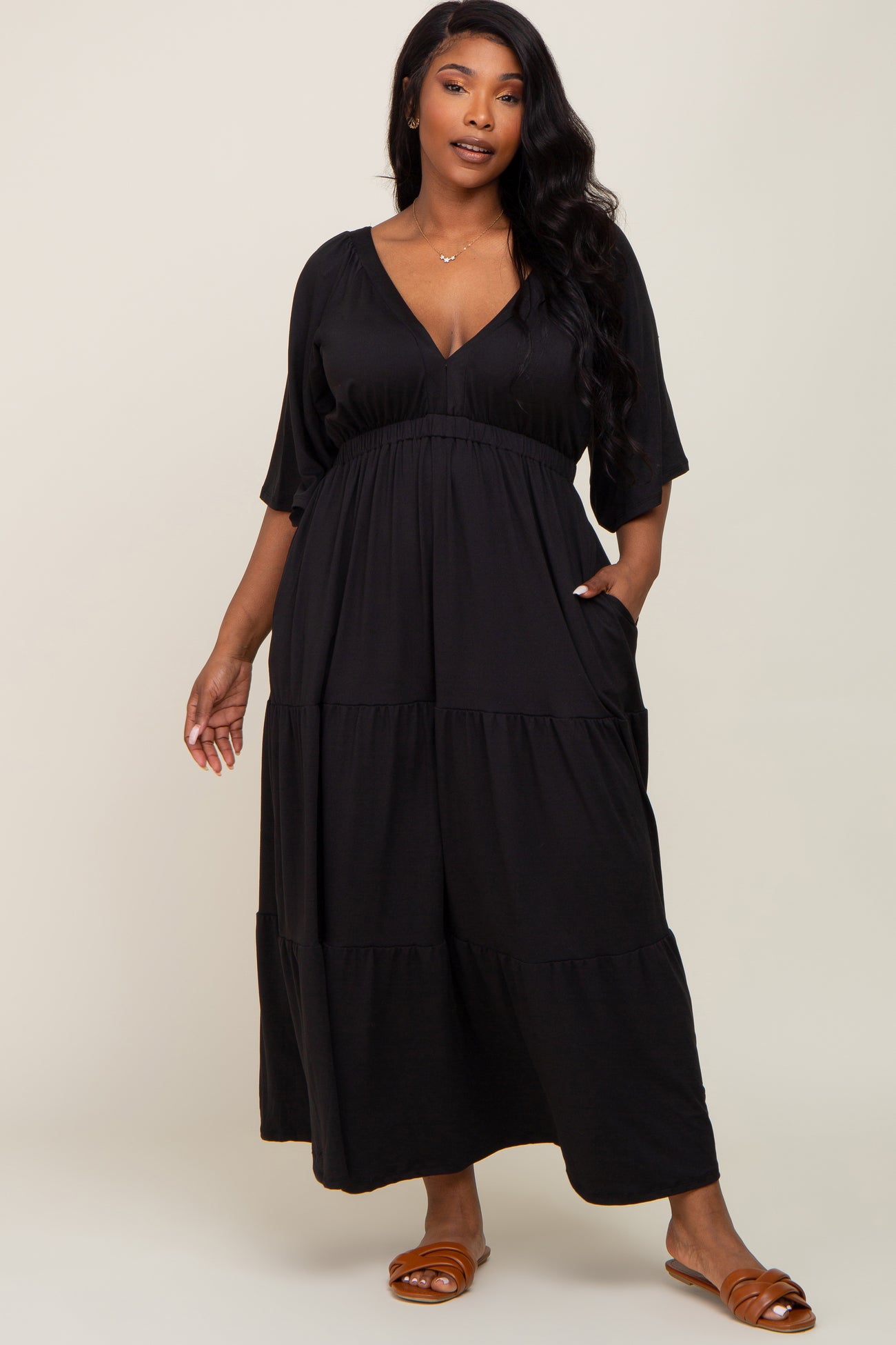 woman wearing a black plus size tiered maxi dress with a deep v-neck and pockets
