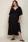 woman wearing a black maternity plus maxi dress with a v-neck and tiered design, showing off her baby bump