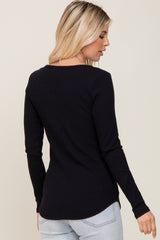 woman wearing a black ribbed long sleeve top, shown from the back with a slight curve at the hemline