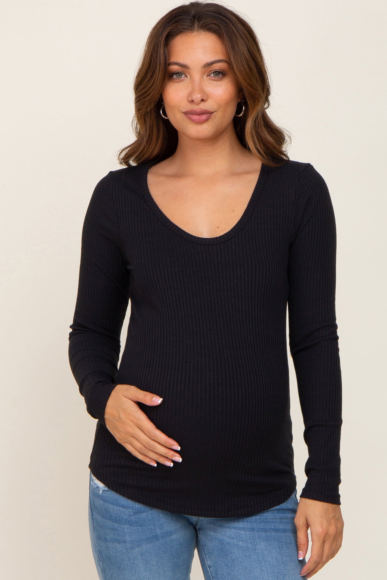 woman wearing a black ribbed long sleeve maternity top and gently cradling her baby bump