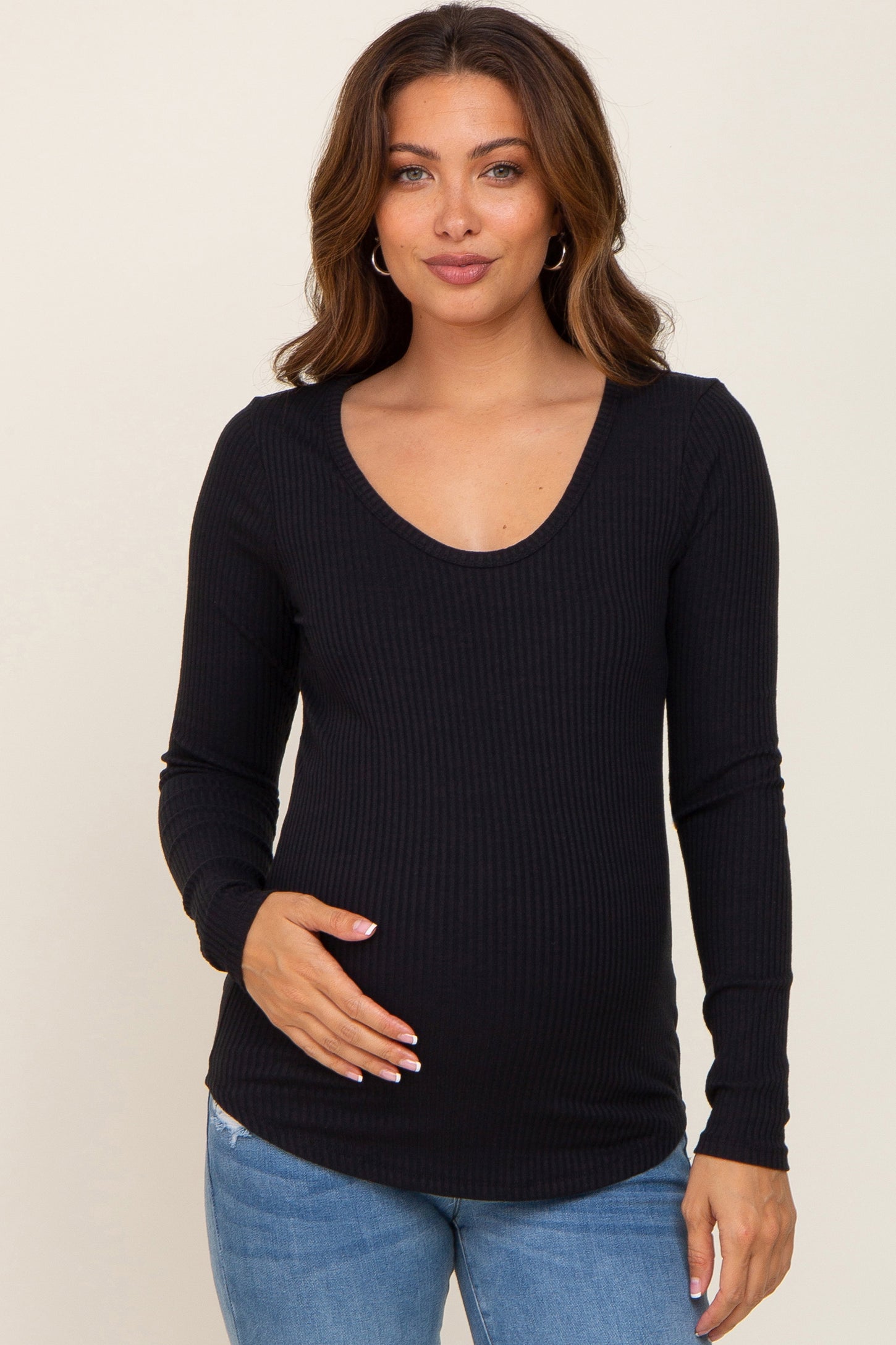 woman wearing a black ribbed long sleeve maternity top and gently cradling her baby bump