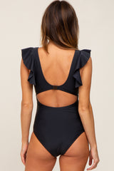 woman wearing a black one-piece swimsuit with ruffle details on the shoulders and a cutout back