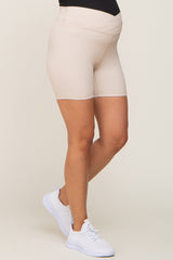 woman wearing beige maternity bike shorts with a supportive waistband and white athletic shoes
