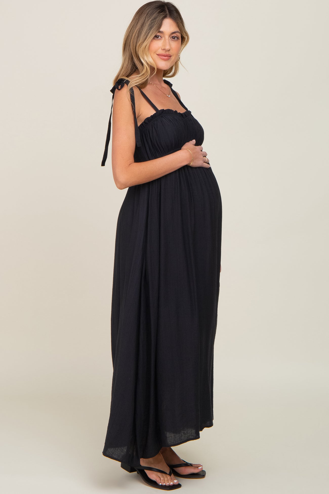 woman wearing a black maternity maxi dress with tie straps and a visible baby bump