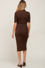 woman wearing a brown ribbed maternity midi dress with a fitted silhouette and short sleeves, showing her baby bump