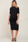 woman wearing a black ribbed maternity dress with short sleeves and a fitted silhouette, showcasing her baby bump