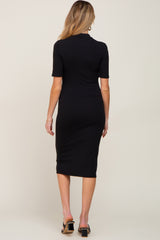 Back view of a woman wearing a black short sleeve ribbed midi dress with a mock neck and black heels