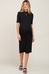 woman wearing a black ribbed maternity dress with short sleeves and a fitted style, showing her baby bump