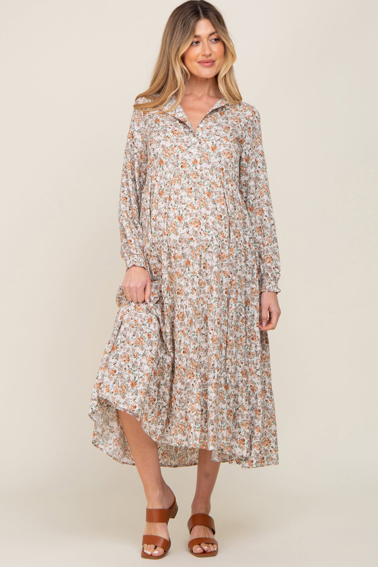 woman wearing a floral print maternity dress with a collared neckline and long sleeves, revealing a baby bump