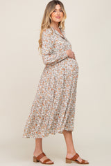woman wearing a floral maternity dress with long sleeves and a baby bump, standing sideways against a neutral background