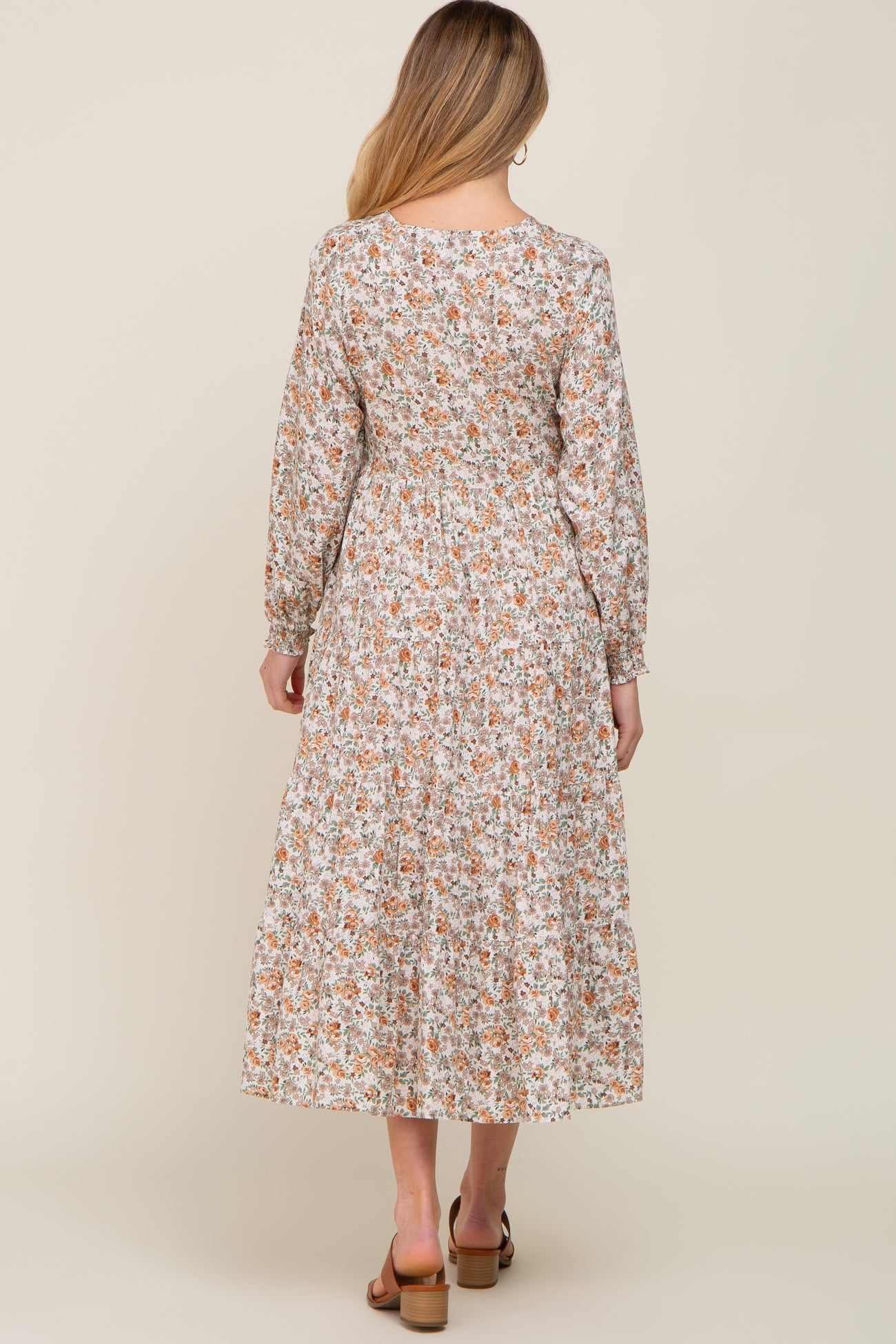 woman wearing a floral long sleeve maternity dress with a tiered skirt, showing the back view