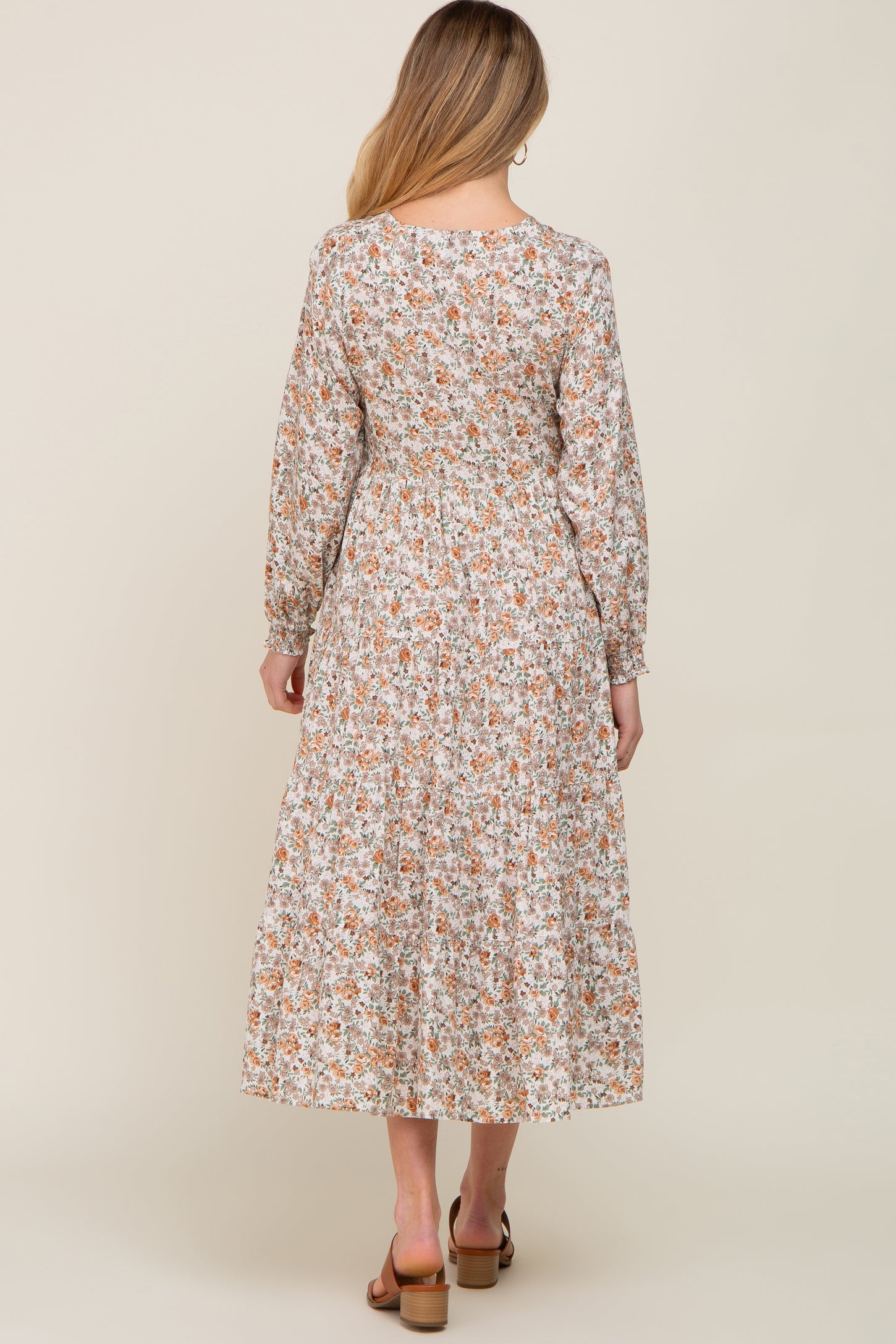 woman wearing a floral long sleeve maternity dress with a tiered skirt, showing the back view