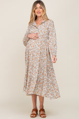 woman wearing a floral midi maternity dress with long sleeves and a collared neckline, holding her baby bump