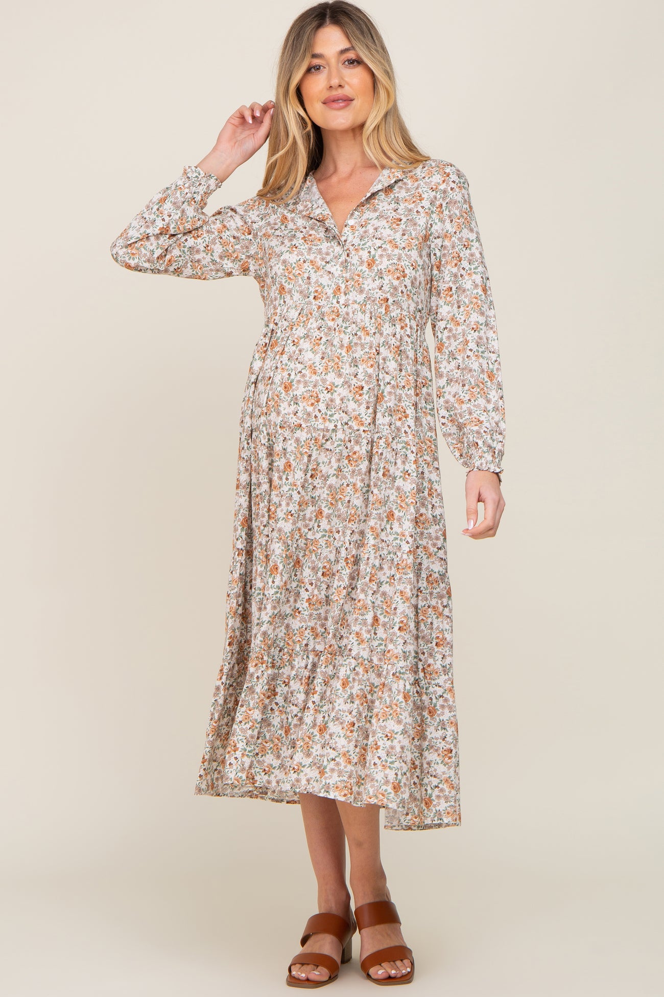 woman wearing a floral maternity dress with long sleeves and a v-neck, showing off her baby bump