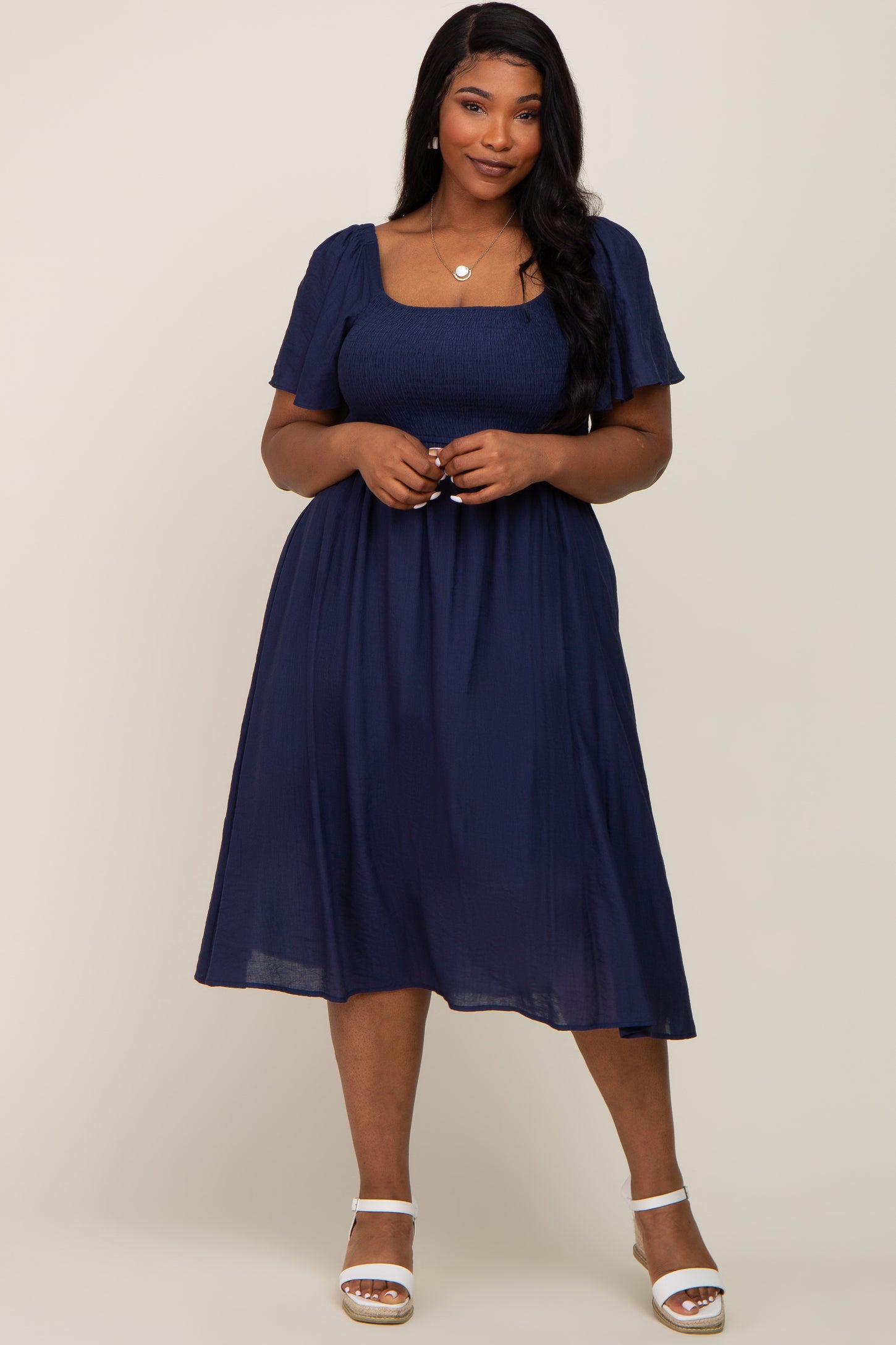 woman wearing a navy blue plus size midi dress with short puff sleeves and a square neckline