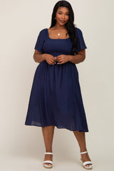 woman wearing a navy blue plus size midi dress with short puff sleeves and a square neckline