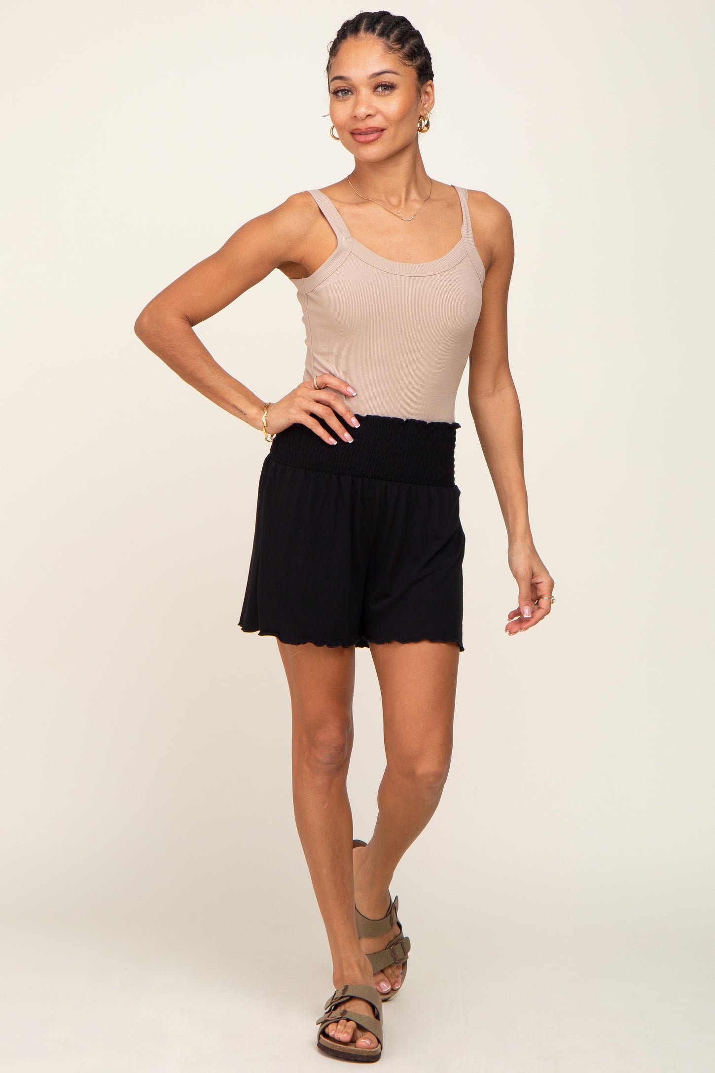 woman wearing a beige ribbed tank top and black elastic-waist shorts with a scalloped hemline