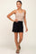 woman wearing a beige ribbed tank top and black elastic-waist shorts with a scalloped hemline
