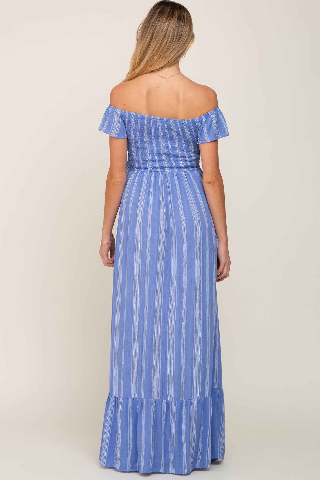 woman wearing a blue striped off-shoulder maternity maxi dress with a ruffled hem and flowing silhouette