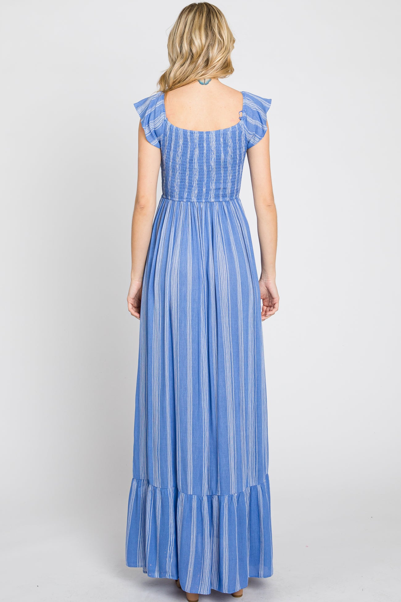 woman wearing a back view of a blue striped maxi dress with ruffle straps and a tiered skirt