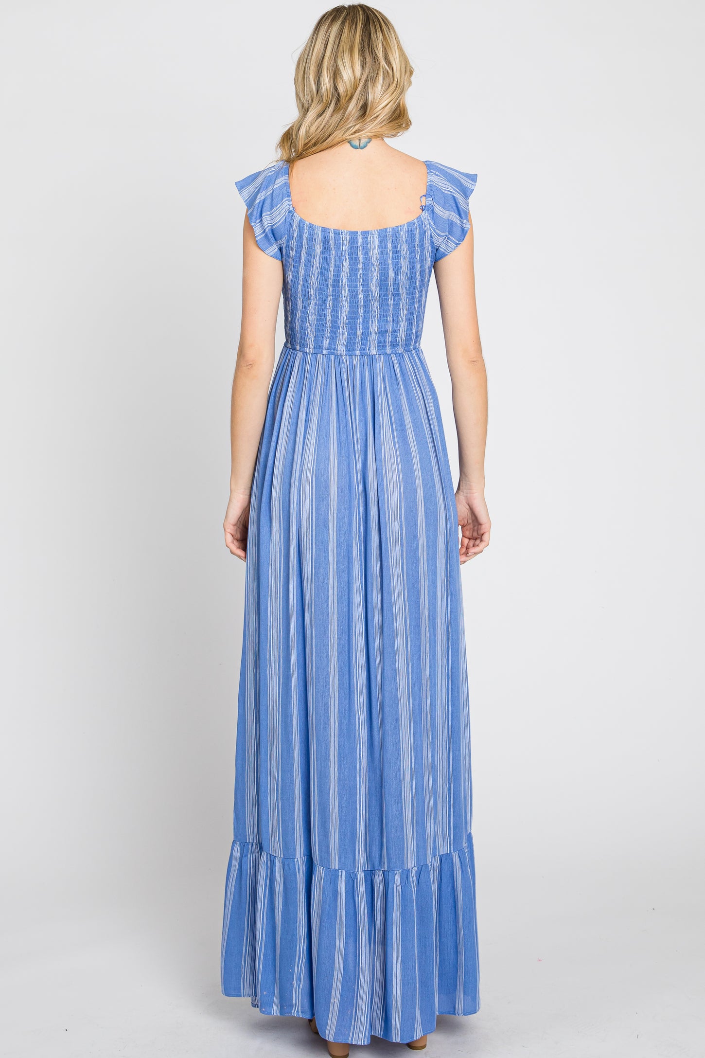 woman wearing a back view of a blue striped maxi dress with ruffle straps and a tiered skirt