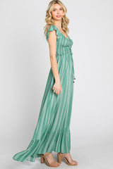 woman wearing a green striped maxi dress with ruffle sleeves and a tie waist, standing sideways on a white background