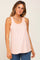 woman wearing a light peach sleeveless tank top with a scoop neckline and relaxed fit, styled with denim jeans