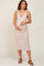 woman wearing a light beige maternity dress with tie shoulder straps and a visible baby bump