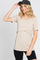 woman wearing a beige short sleeve top with a layered design and smiling while wearing a black cap