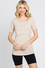 woman wearing a beige short sleeve ribbed top with a layered design and black athletic shorts