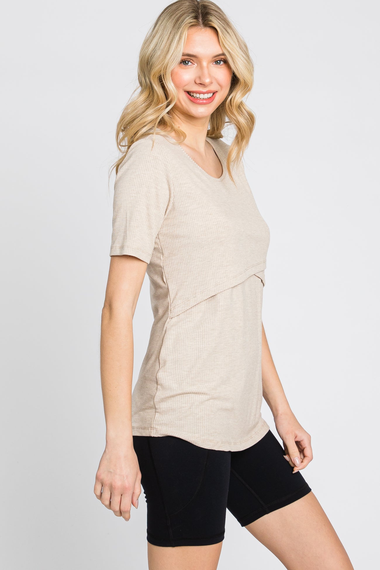 woman wearing a beige short sleeve top with a layered design and black bike shorts