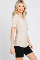 woman wearing a beige short sleeve top with a layered design and black bike shorts