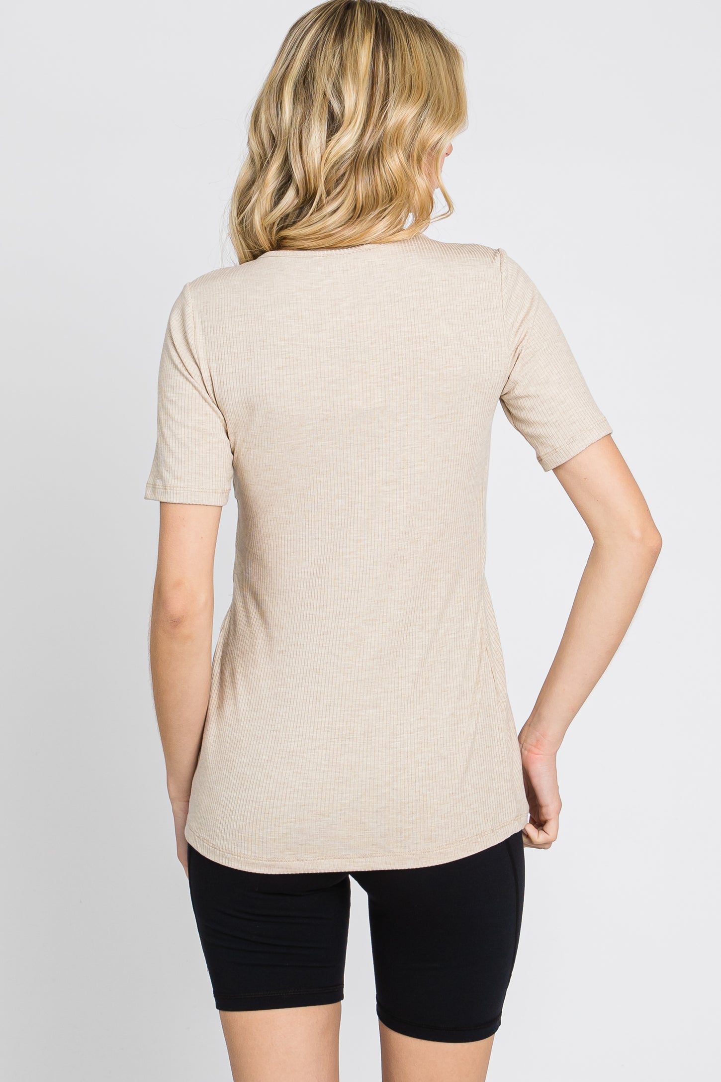 woman wearing a beige short sleeve ribbed top, shown from the back, paired with black shorts