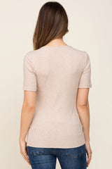 woman wearing a light beige maternity top with short sleeves, viewed from the back, paired with blue jeans