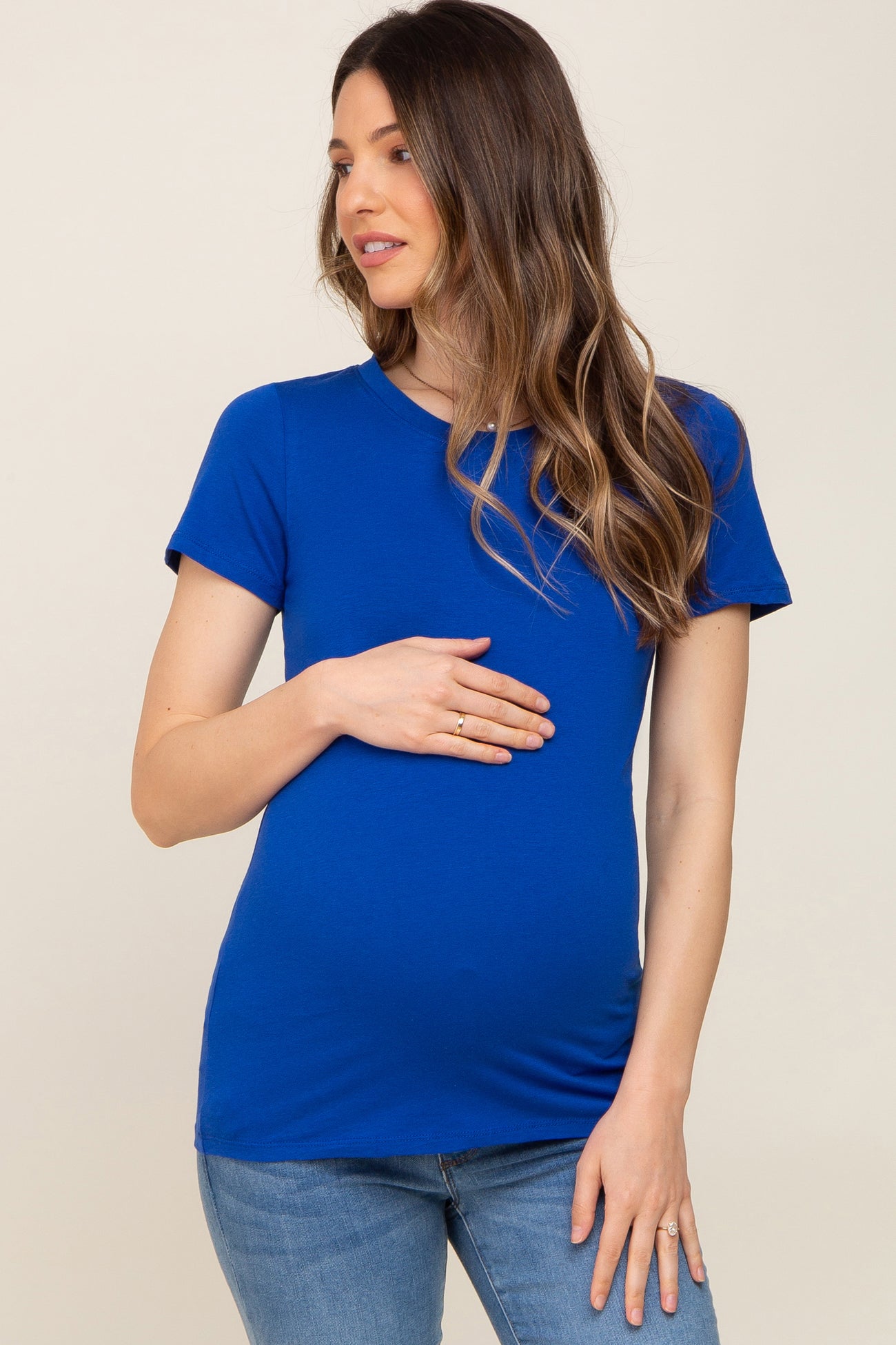 woman wearing a royal blue short sleeve maternity top and holding her baby bump
