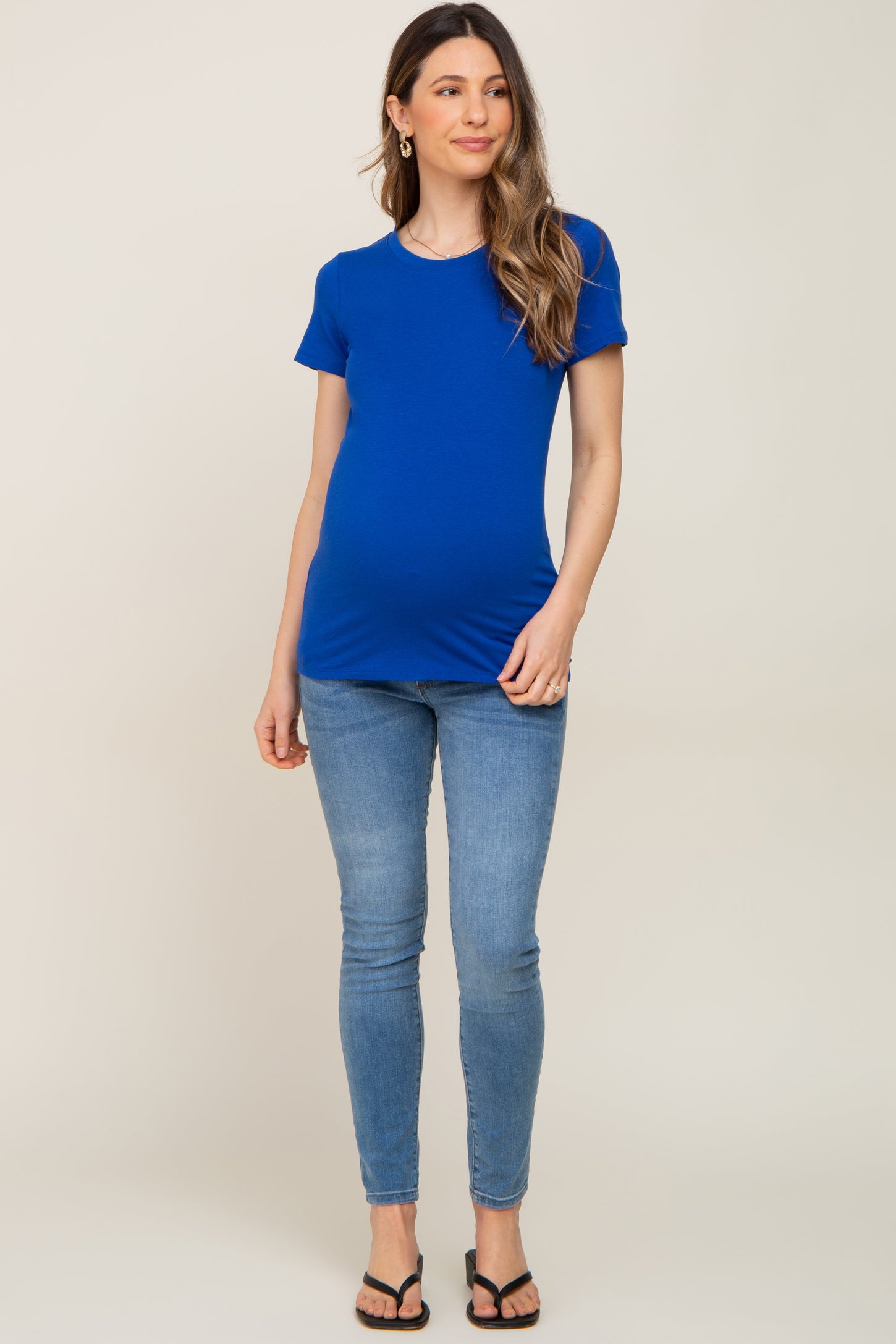 woman wearing a bright blue maternity t-shirt and skinny jeans, showing her baby bump