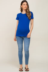 woman wearing a bright blue maternity t-shirt and skinny jeans, showing her baby bump
