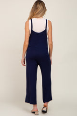 woman wearing a navy blue maternity jumpsuit with adjustable straps, showing the back view.
