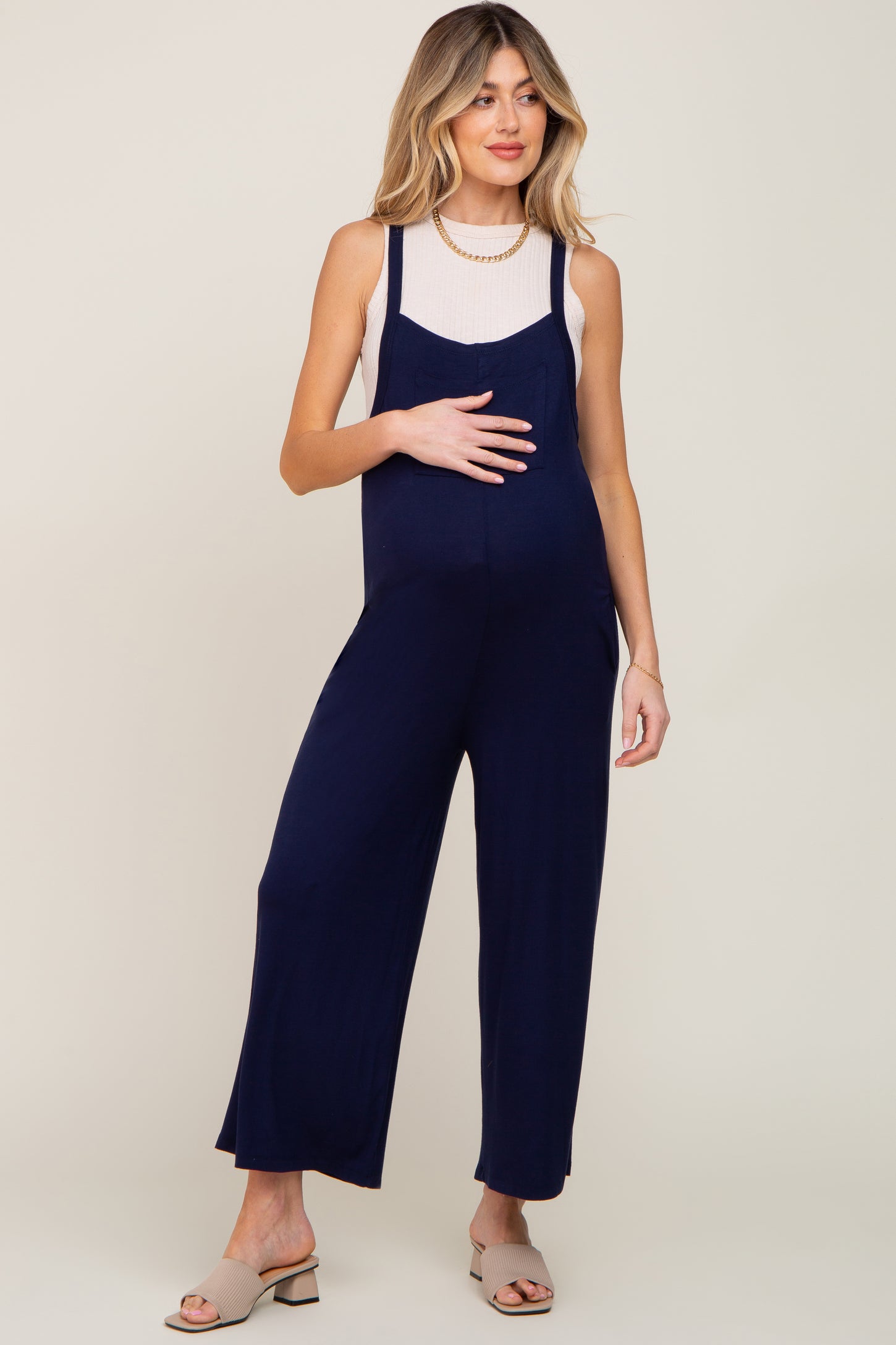 woman wearing a navy blue maternity jumpsuit with a fitted tank top and holding her baby bump