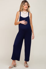 woman wearing a navy blue maternity jumpsuit with a fitted tank top and holding her baby bump