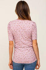 woman wearing a lilac short sleeve top with a floral print and ruching detail, viewed from the back