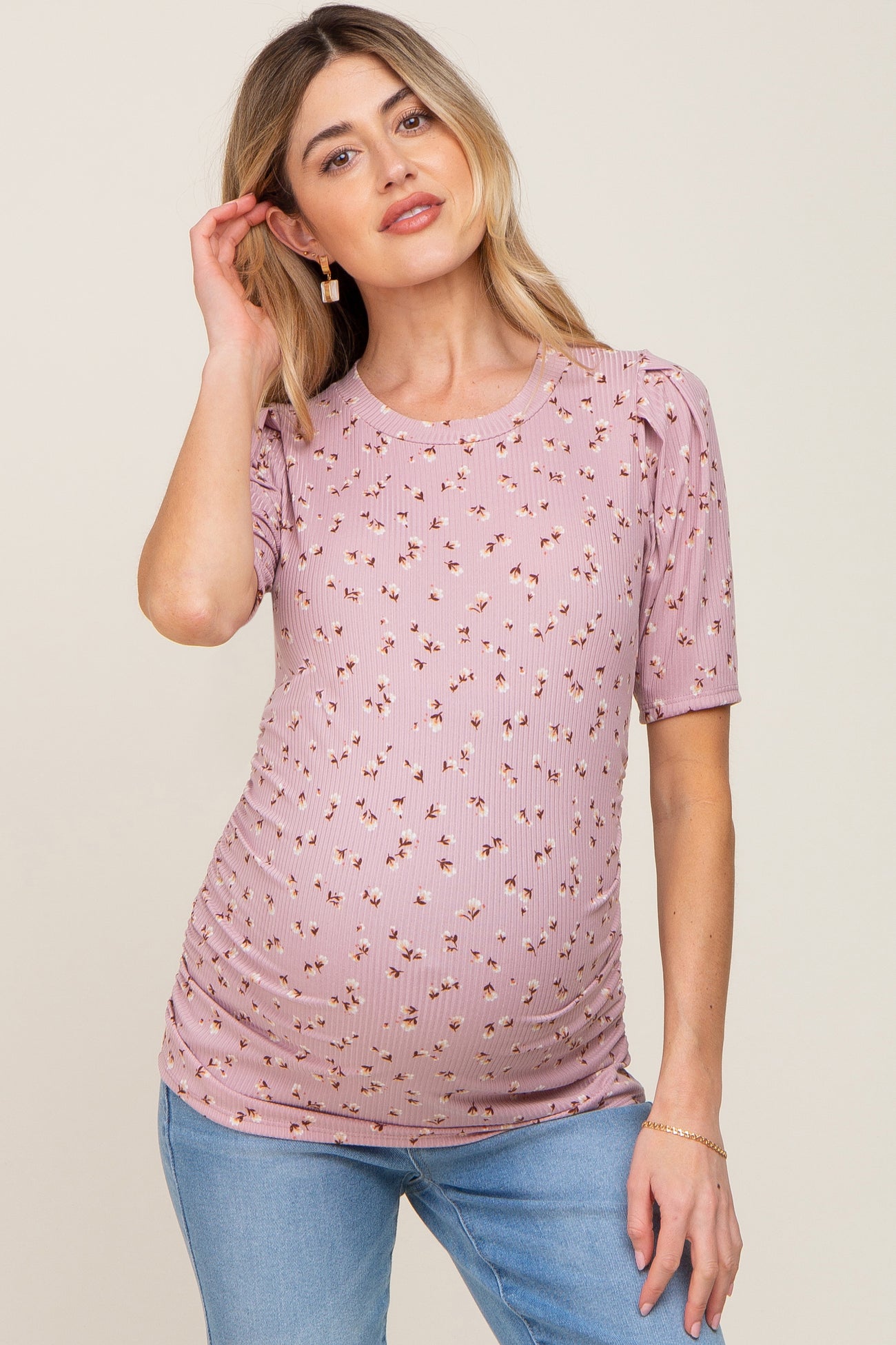 woman wearing a pink floral ribbed maternity top with short sleeves and a visible baby bump