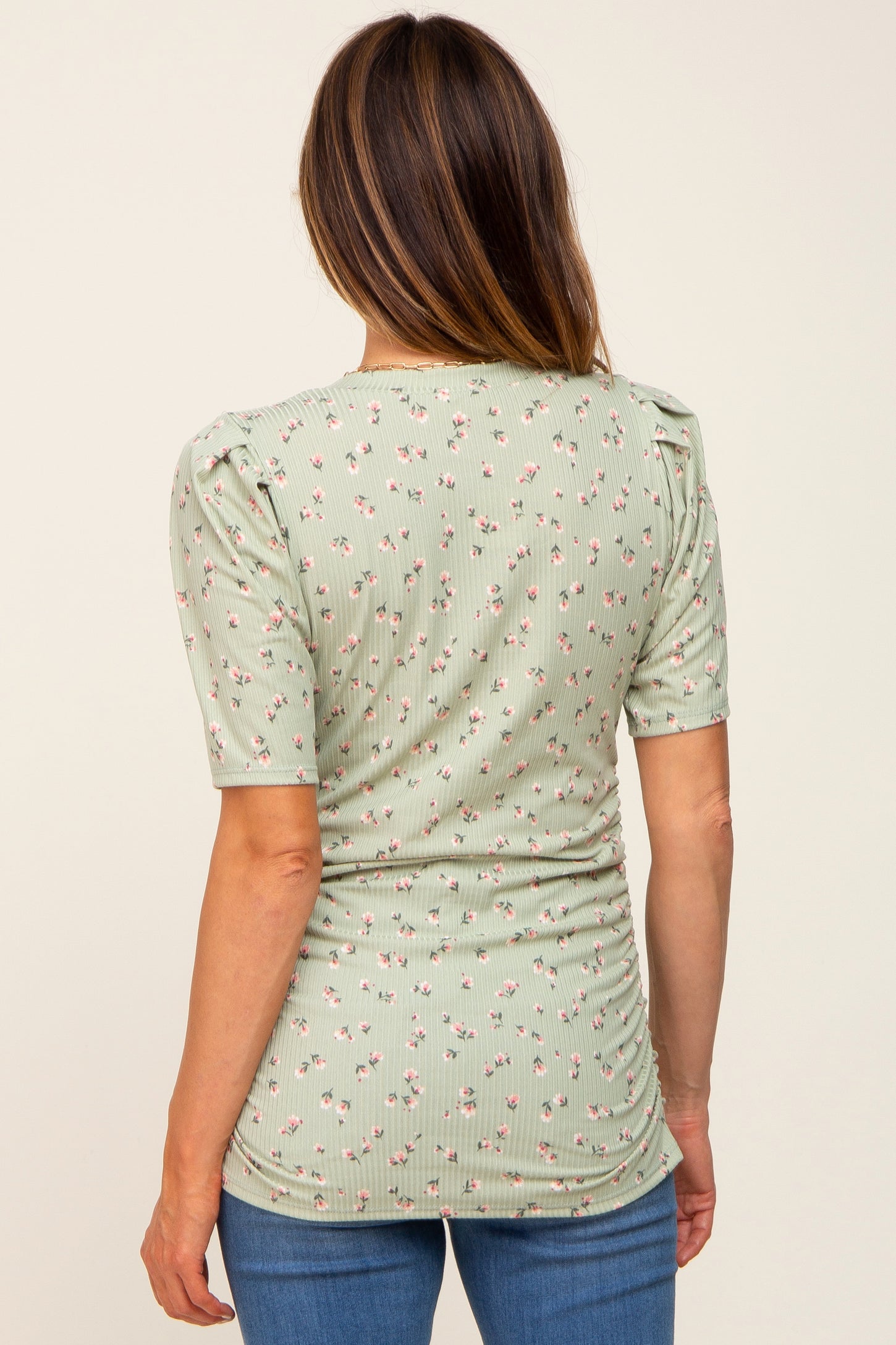 woman wearing a mint green floral print top with puff sleeves and a fitted silhouette, viewed from the back