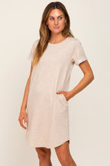 woman wearing a beige short sleeve t-shirt dress with rolled cuffs and side pockets