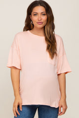 woman wearing a light peach oversized maternity t-shirt with short sleeves and a pocket on the front