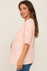 woman wearing a soft pink short sleeve maternity top with a pocket and showing her baby bump